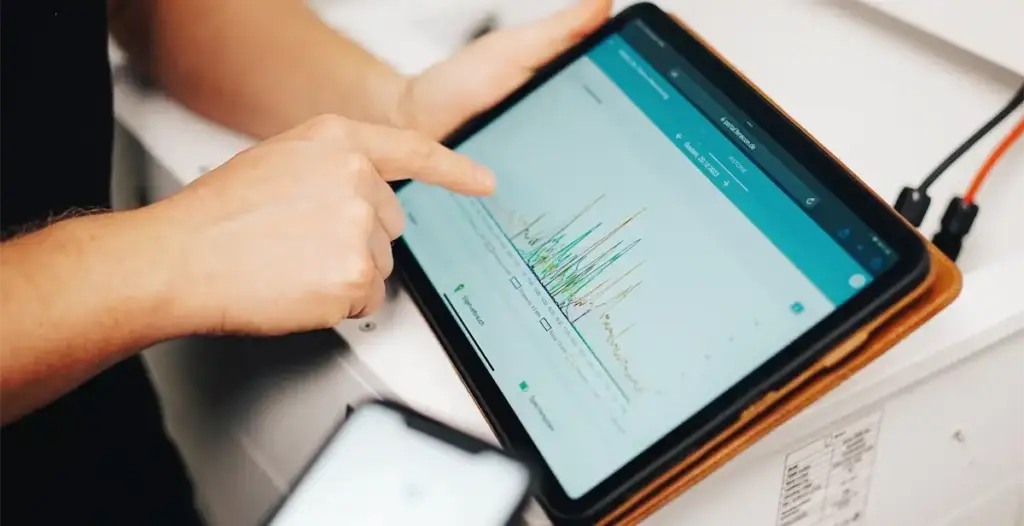 Ein Finger zeigt auf ein Diagramm auf einem Tablet das mit der Stromintelligenz App Software geöffnet ist
