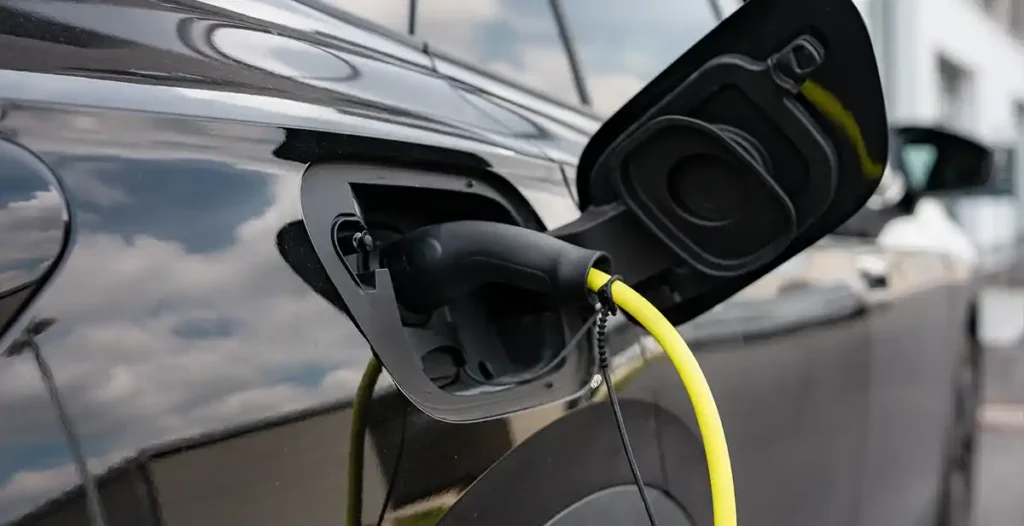 Ein schwarzes Elektroauto wird über ein gelbes Ladekabel an einer Wallbox geladen