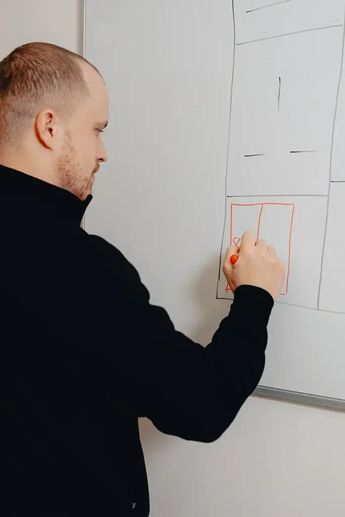 Markus Steinbock von der IntHome Elektrotechnik GmbH zeichnet ein Diagramm auf eine weiße Tafel und erläutert technische Details, vermutlich im Rahmen einer Schulung oder eines Meetings.