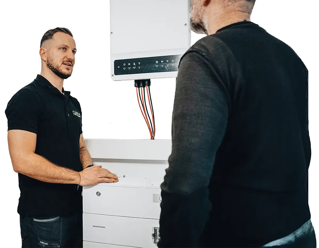 Geschäftsführer Markus Zink erklärt einem Kunden die Funktionen eines Stromspeichers an der Wand bei einer Beratung