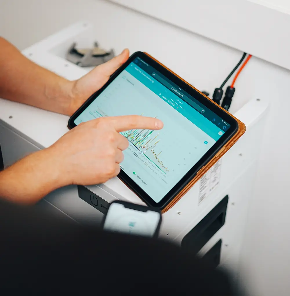Person zeigt auf Tablet mit grafischer Übersicht eines Energiemanagement Systems