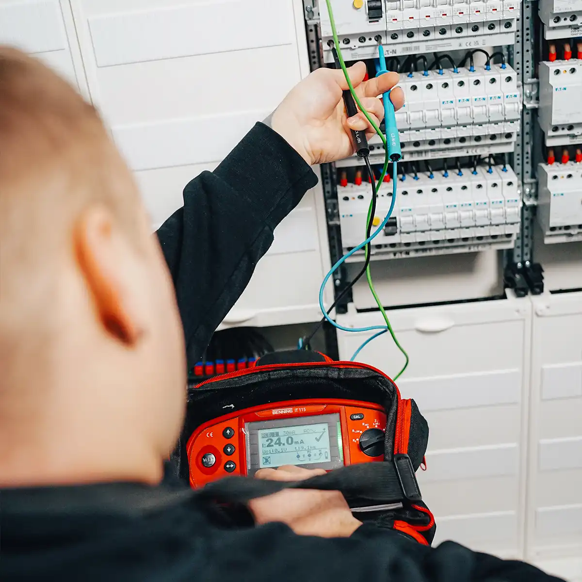 Ein Techniker von IntHome Elektrotechnik GmbH führt Service an einer Schalttafel durch. Er nutzt ein spezielles Messgerät, um elektrische Werte zu überprüfen und die korrekte Funktion der Installation sicherzustellen. Diese Szene verdeutlicht die Präzision und Sorgfalt bei der Arbeit von IntHome.