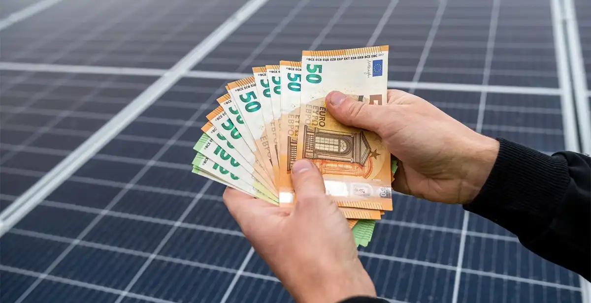 Geldscheine vor den Platten einer Photovoltaikanlage. Thematisch passend zu den Förderung für Solaranlagen in 2026