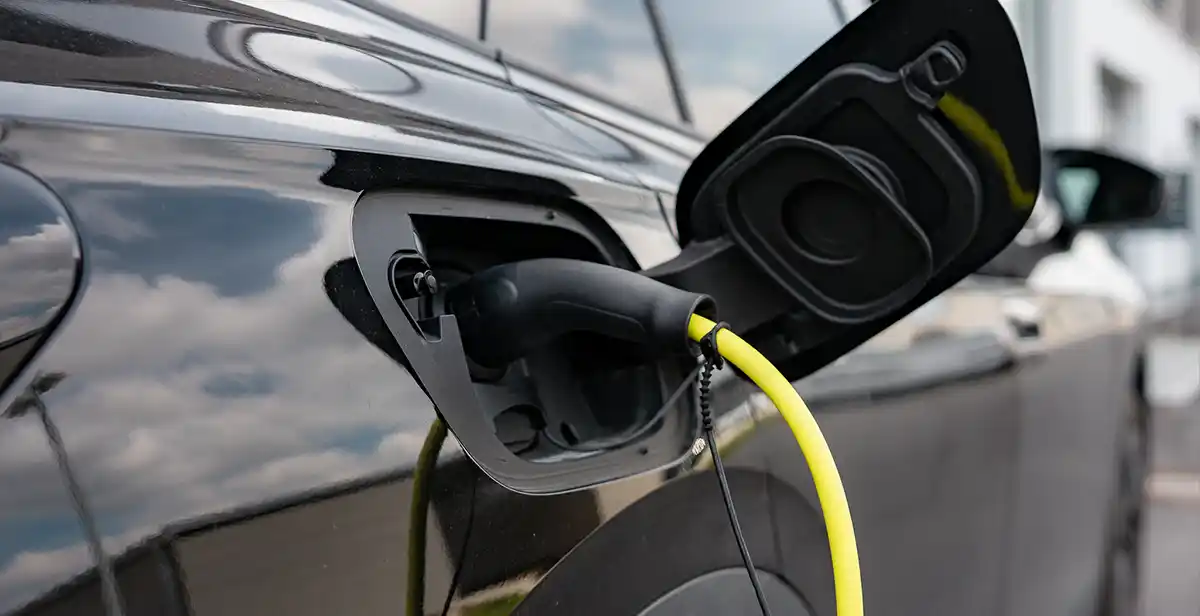 Ein schwarzes Elektroauto wird über ein gelbes Ladekabel an einer Wallbox geladen