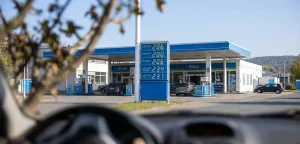 Auto fährt an Tankstellen Säule vorbei mit Anzeige von hohen Spritpreisen